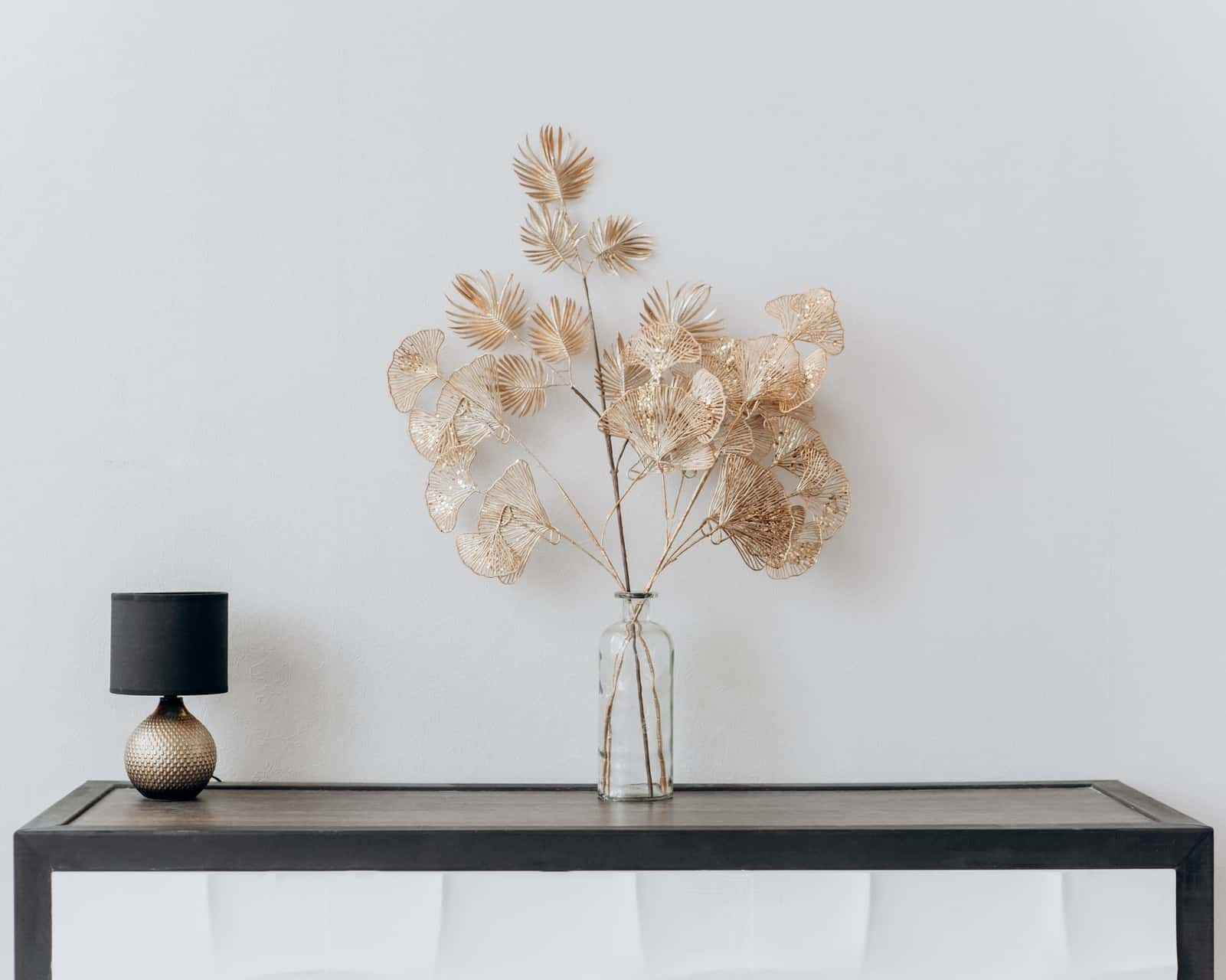 Minimalistisk indretning med fint sort bord, en blomst og en minimalistisk bordlampe. 