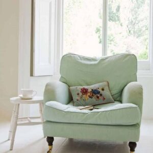 Billede af en opholdsstue der er minimalistisk indrettet med en pastel grøn farvet lænestol.