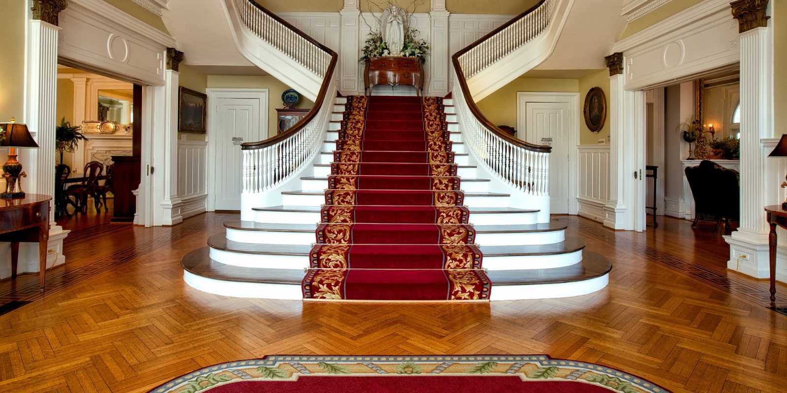 Billede af en stor flot entre, med en stort trappe og et persisk tæppe i midten af trappen